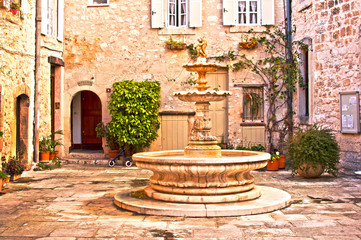 Fototapeta na wymiar Fontaine d'un village médiéval sur une place pavée