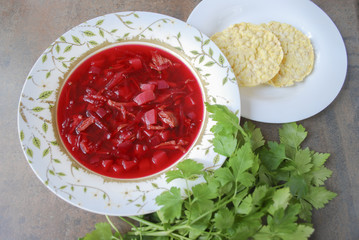 Beetroot soup in plate with parsley and corn crackers on brown background. Finished dish. Ukrainian and Russian cuisine.