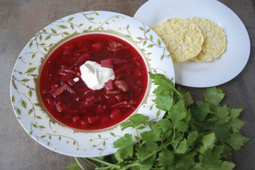 Beetroot soup in plate with parsley and corn crackers on brown background. Finished dish. Ukrainian and Russian cuisine.