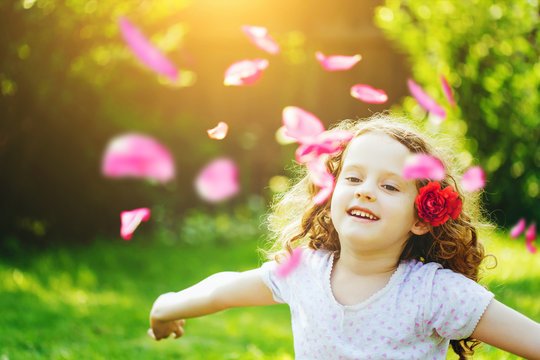Happy child hand up, enjoying freedom with flying flower petals