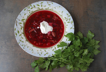 Beetroot soup in plate with parsley on brown background. Finished dish. Ukrainian and Russian cuisine. 