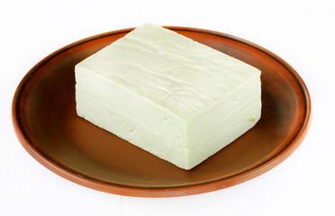 Tofu cheese on a clay plate isolated on white background