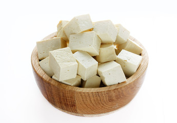 Tofu cubes in a wooden bowl isolated on white background