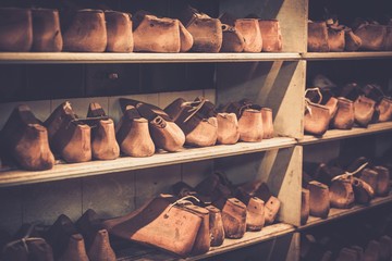 Various of vintage wooden shoe lasts in a row on the old shelves.