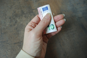 Female hand holds folded currency note (ten euro).