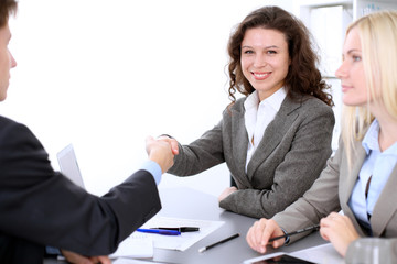 A group of business people at a meeting on the background of office. Business handshake. Focus on a beautiful blonde