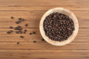 Coffee beans in bowl on wooden background