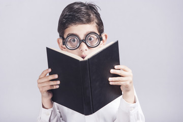 Funny nerdy little boy reacts while reading a book