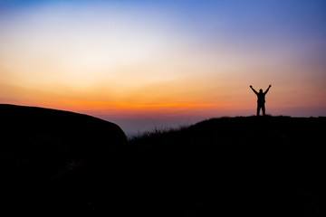 Fototapeta na wymiar The man is show his hand in the sky at the morning on the mountain