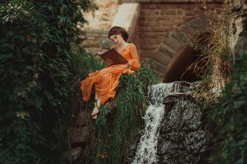 The beautiful countess in a long orange dress sits near a source of water and reading a book, elf, Princess in vintage dress, the queen of the forest,fashionable toning creative computer colors