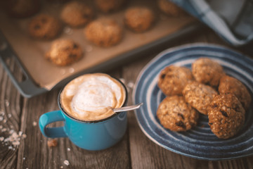 Baking tray and a plate of oatmeal cookies on the wooden table