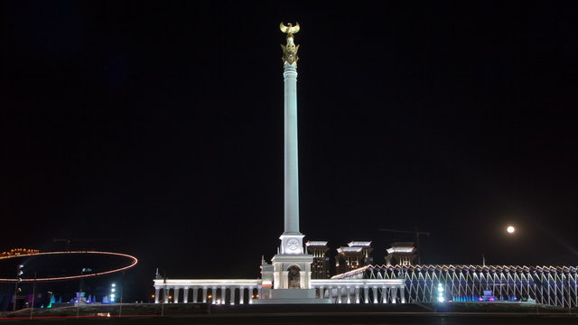 Stele monument Kazakh Eli with bird Samruk and Palace of Independence timelapse hyperlapse at night.
