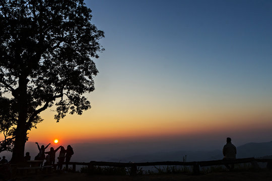 Peoples and trees silhouetted with stunning sunset