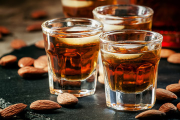 Cold whiskey with ice in a glass and a snack almonds, selective