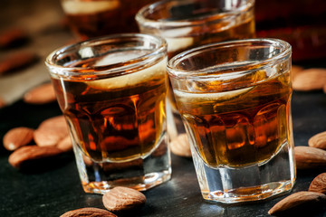 Cold whiskey with ice in a glass and a snack almonds, selective