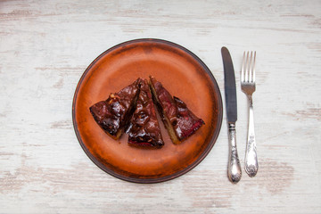 Piece of homemade tart with caramel filling on a clay plate