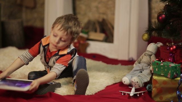 Boy with tablet PC near christmas tree