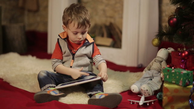 Boy with tablet PC near christmas tree