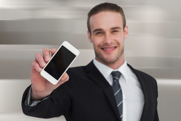 Composite image of smiling businessman showing his smartphone