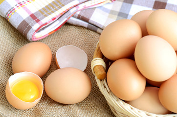 Wicker basket with eggs and raw egg on a linen tablecloth