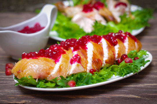 roasted baked chicken breast with cranberry and pomegranate sauce in a gravy boat on a wooden table