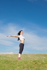 Fototapeta premium Girl dancing on background of sky. Attractive brunette posing on