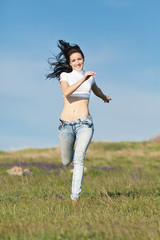 Naklejka na ściany i meble Barefoot brunette in jeans runs along field