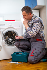 Obraz premium Repairman is repairing a washing machine on the white background. Entering malfunction
