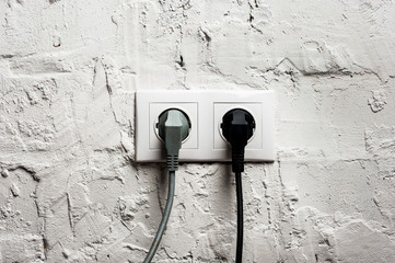 Double electrical socket with plugged cables.