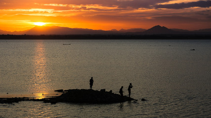 Naklejka na ściany i meble People fishing at sunset