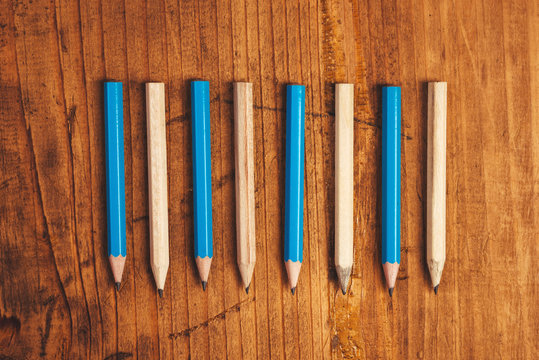 Blue and brown lined up pencils on rustic wooden table