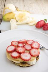 Stack of golden pancakes with strawberries, banana,