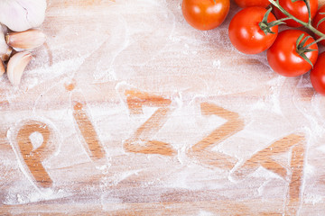 Tasty pizza ingredients on a wooden table. hand written word pizza