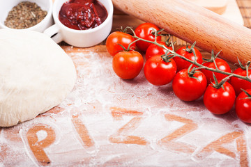 Tasty pizza ingredients on a wooden table. hand written word pizza