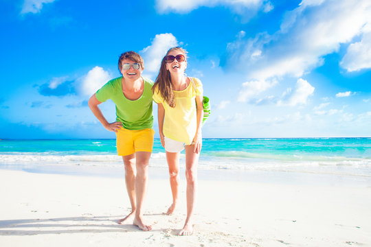 happy young caucasian couple in sunglasses smiling on beach