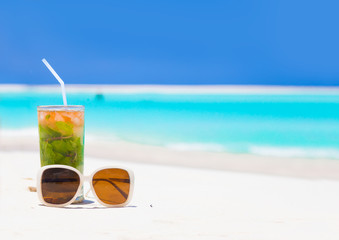 Exotic cocktail and sunglasses, caribbean beach on background