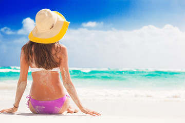 Fototapeta na wymiar woman in bikini and straw hat having fun on tropical beach