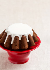 Chocolate cake with white frosting on a red stand.