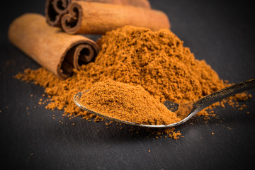 Cinnamon sticks with cinnamon powder on stone plate