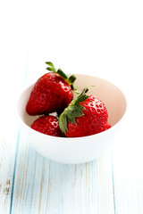 Ripe red strawberry on a blue wooden table