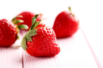 Ripe red strawberry on a pink wooden table