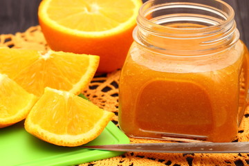 Obraz na płótnie Canvas Sliced oranges and orange jam in glass jar