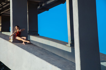 Young beautiful woman gymnast posing on bridge girder