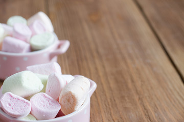 delicate, delicious marshmallows into a bowl on a wooden backgro