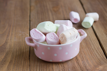 delicate, delicious marshmallows into a bowl on a wooden backgro