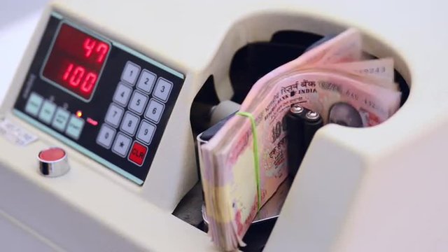 Locked-on shot of Indian currency notes being counted in a machine