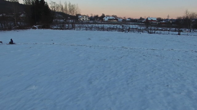 Father pulling slade and kids having fun in winter, aerial view