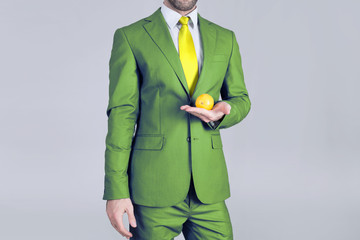 Healthy man in green suit holding a lemon 