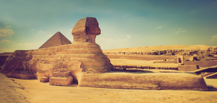 The full profile of the Great Sphinx with the pyramid in the background in Giza.