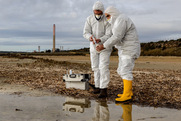Experts Analysis Water / Two technicians levying of water samples from the river to perform the...